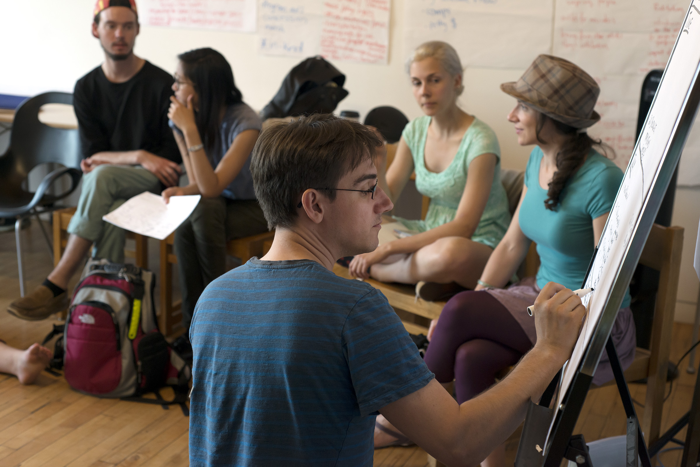 A TENT Youth participant is writing something on a whiteboard in the classroom