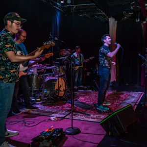 A performer sings karaoke accompanied by a live band