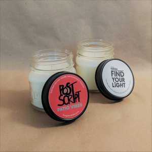 Two candles in mason jars with black lids.