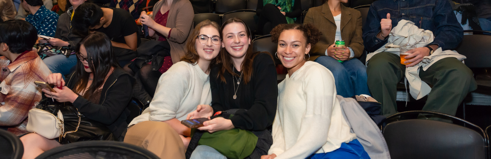 Next Stage audience members sit in theatre seats smiling at camera