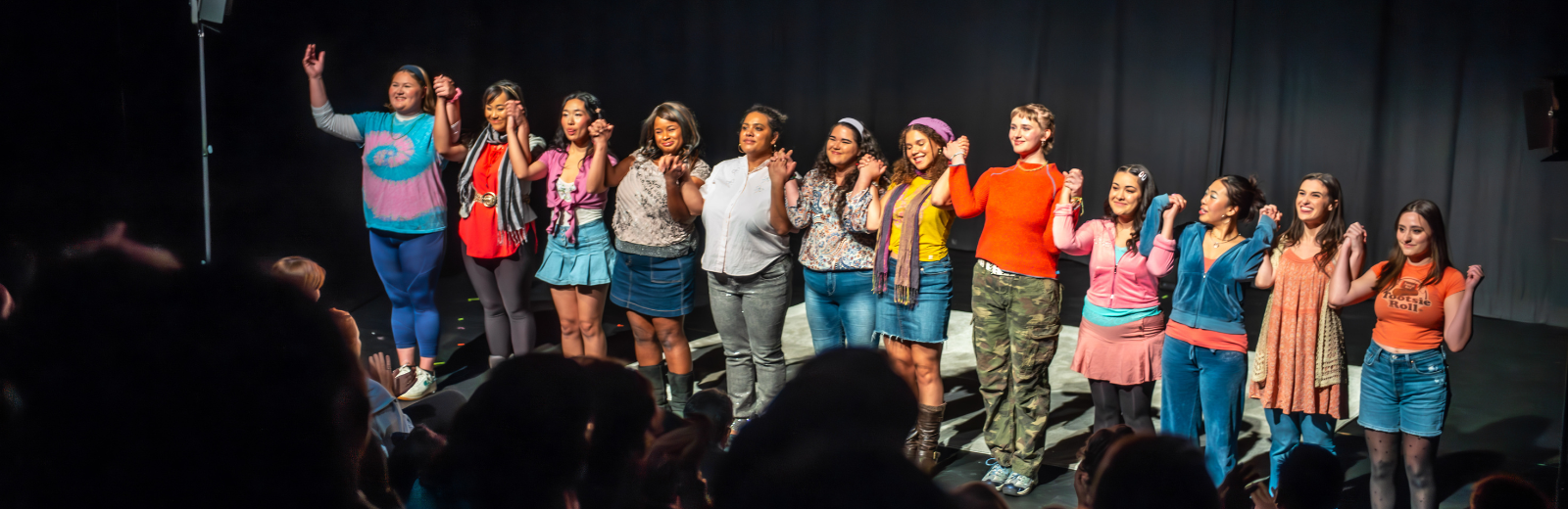Next Stage artists hold hands and bow to a clapping audience