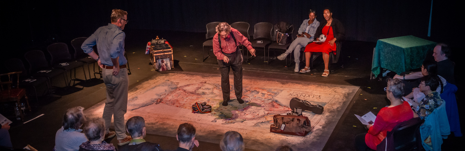 Next Stage artist performs on stage standing on a large map with audience surrounding them 