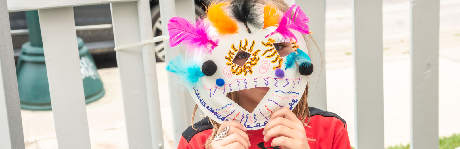 A kid holds up the mask they made at the KidsFest Club