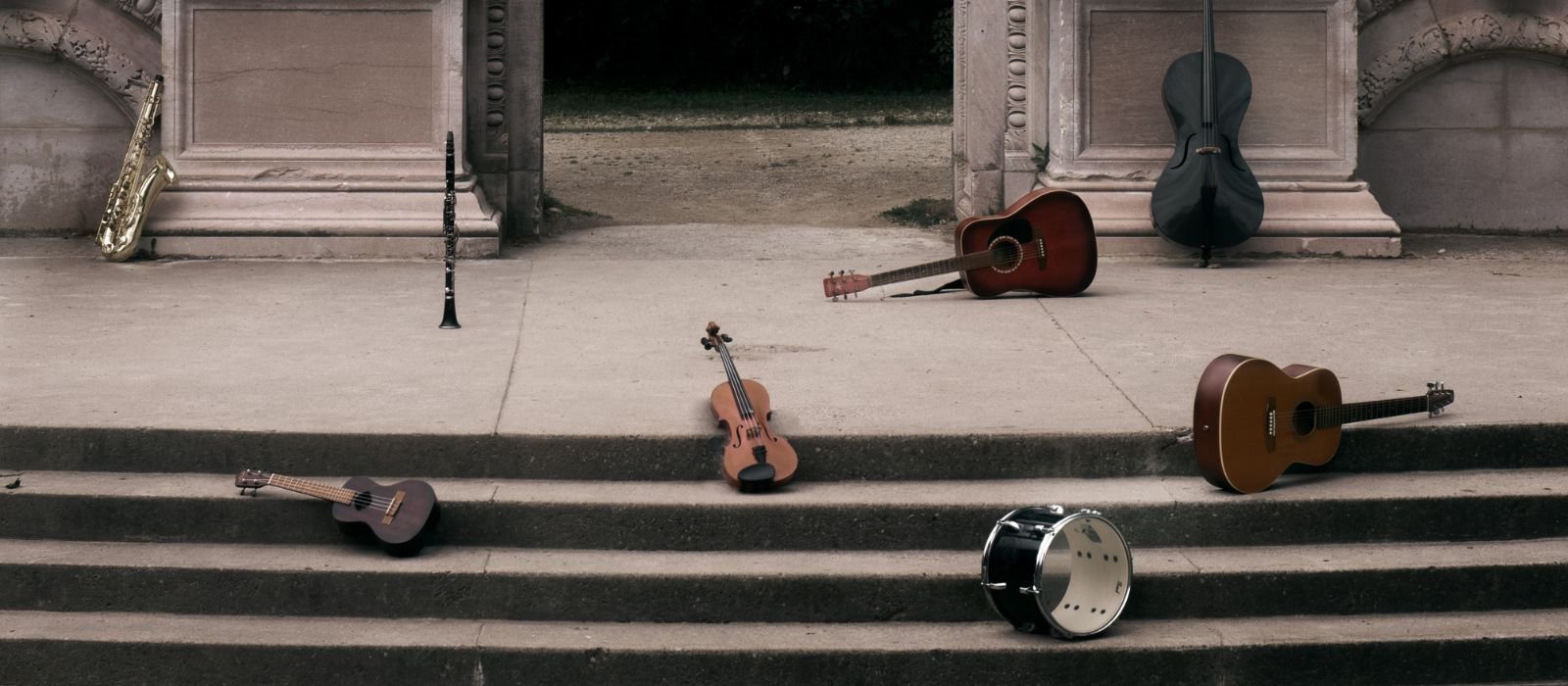 Musical instruments lay on stone steps, with an archway and columns in the background.