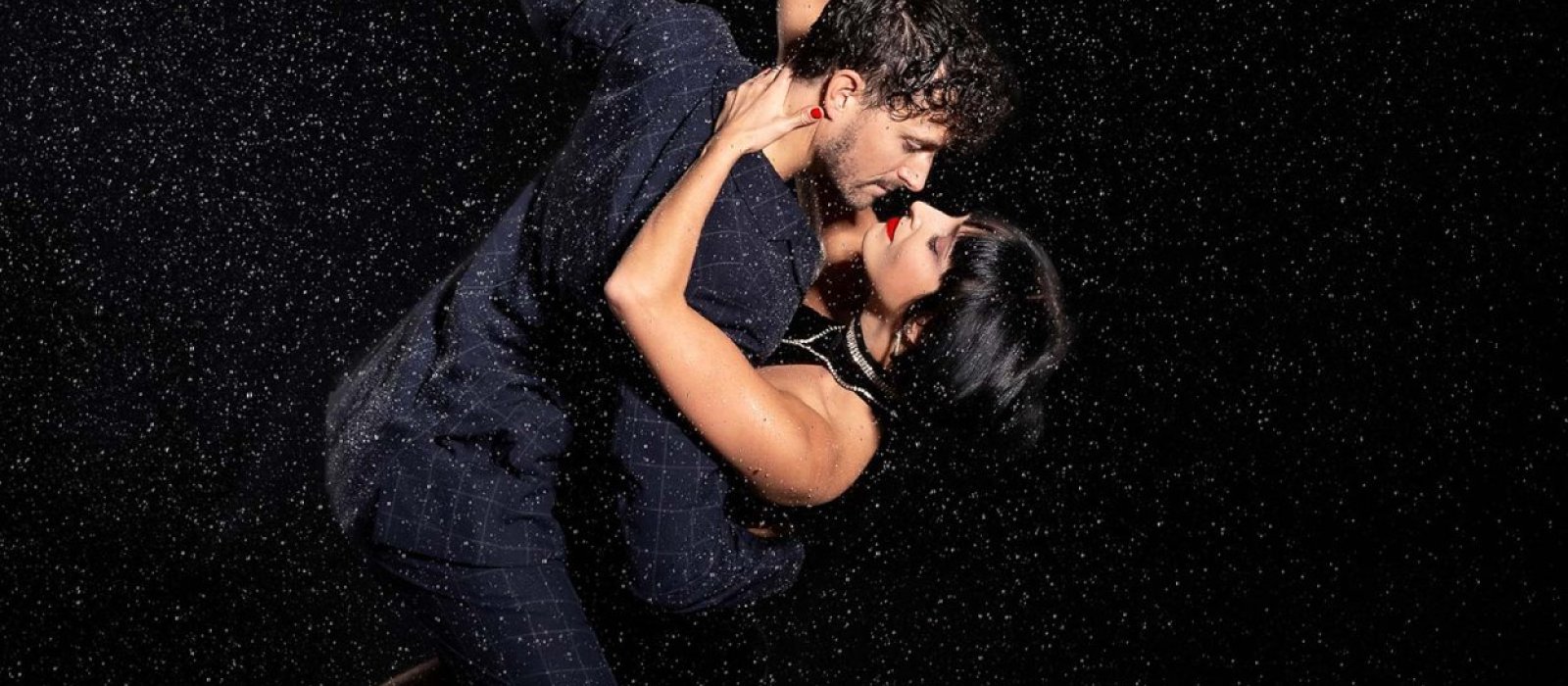 Two tango dancers wearing black in the rain.